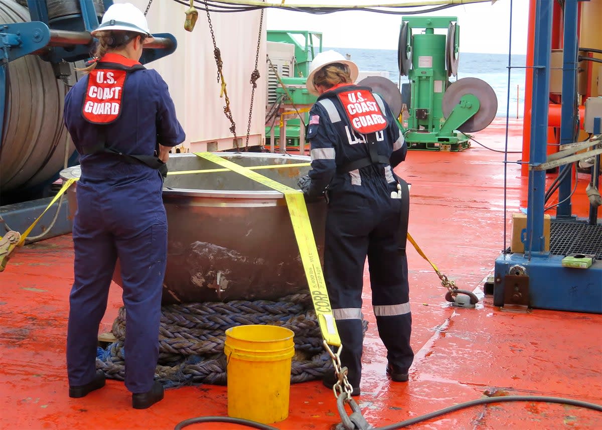 US Coast Guard marine safety engineers conduct a survey of the aft titanium endcap from the Titan submersible (AP)