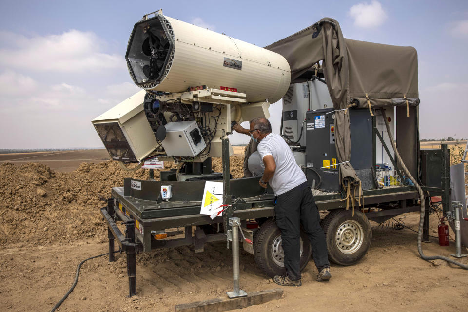 An Israeli police officer demonstrates a new laser defense system designed to intercept explosives-laden balloons launched from the Gaza Strip into Israel, on the Israeli Gaza border, Sunday, Aug. 30, 2020. Hamas-linked activists have sent dozens of the balloons into Israel in recent weeks, scorching large areas of farmland in southern Israel. Israeli police say the new system has a 90% success rate when activated. (AP Photo/Tsafrir Abayov)