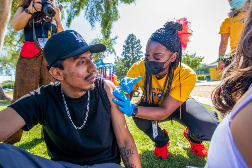 Asia Hartford, LVN, right, administers a covid vaccine to Luis Fernandez