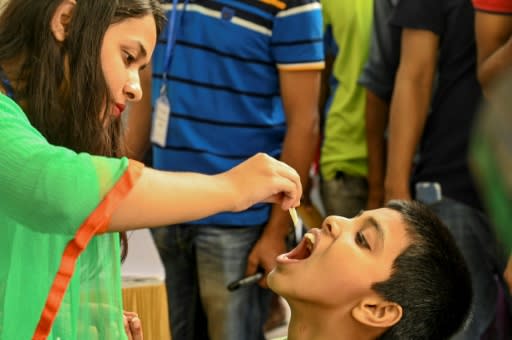 A Bangladeshi child receives an oral cholera vaccine dose from a health worker in Dhaka