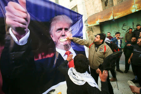 FILE PHOTO: Palestinian demonstrators throw shoes on a poster depicting U.S. President Donald Trump during a protest in the West Bank city of Hebron February 24, 2017. REUTERS/Mussa Qawasma/File Photo