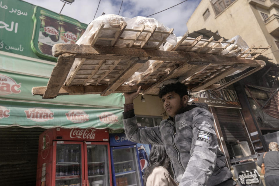 FILE - An Egyptian vendor carries a bread tray at a popular market in Cairo, Egypt, on Jan. 26, 2024. The Egyptian pound slipped sharply against the dollar on Wednesday March 6, 2024 after Egypt’s central bank raised its main interest rate and said it would allow the currency's exchange rate to be set by market forces. The rising cost of basic goods has deepened the hardships faced by middle-class and poor Egyptians. (AP Photo/Amr Nabil, File)