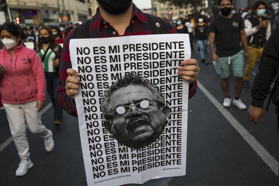 A man holds a poster with an image of Peru's newly sworn-in President Manuel Merino with a message that reads in Spanish: "He is not my president," during a protest by people who are refusing to recognize the new government, in Lima, Peru, Wednesday, Nov. 11, 2020. On Tuesday, Peru swore in Merino, the former congressional leader as president, after the legislature booted President Martin Vizcarra from office on Monday. (AP Photo/Rodrigo Abd)