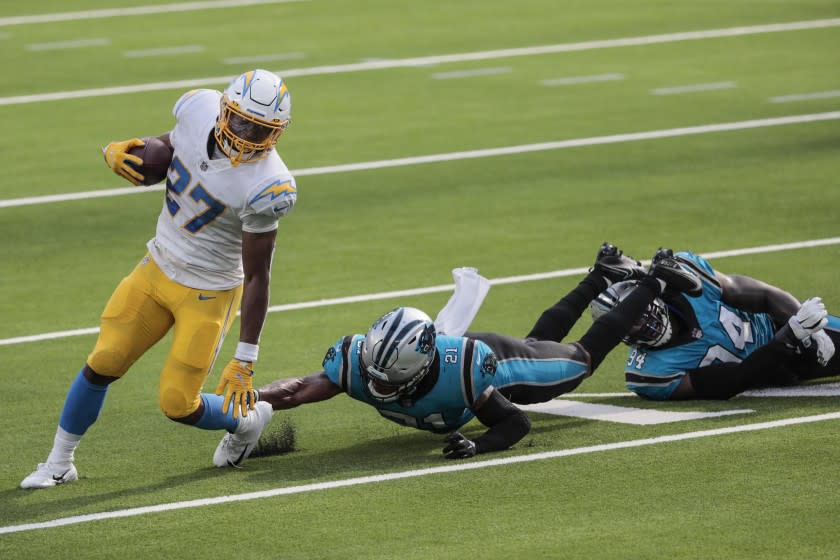 Inglewood, CA, Sunday, September 27, 2020 - Los Angeles Chargers running back Joshua Kelley (27) slips past Carolina Panthers outside linebacker Jeremy Chinn (21) and Carolina Panthers defensive end Efe Obada (94) during a second half drive at SoFi Stadium. (Robert Gauthier/ Los Angeles Times)