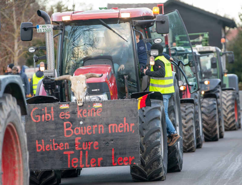 The skull of a dead cow and a poster with the slogan "If there are no more farmers, your plates will remain empty" are attached to a tractor at a farmers' association rally against the German government's austerity plans. Stefan Puchner/dpa