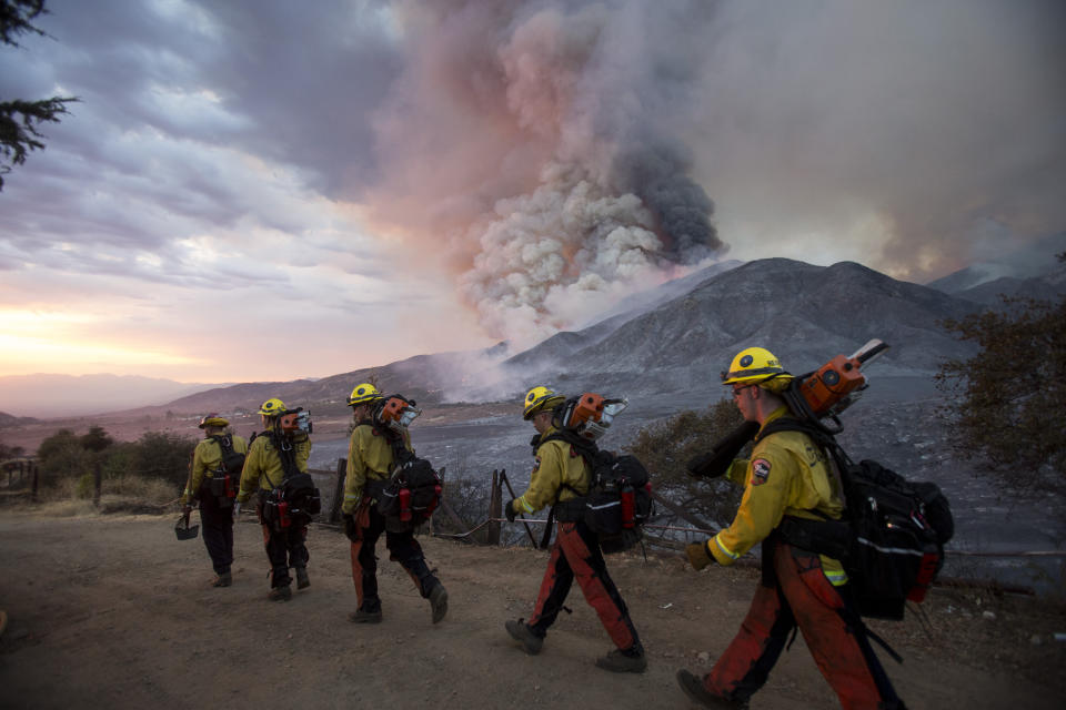 Members of firefighters crew walk in line on Sept. 5, 2020 in Yucaipa, Calif. Firefighters trying to contain the massive wildfires in Oregon, California and Washington state are constantly on the verge of exhaustion as they try to save suburban houses, including some in their own neighborhoods.(AP Photo/Ringo H.W. Chiu)