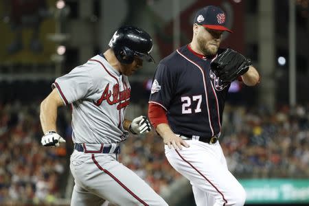 Jul 20, 2018; Washington, DC, USA; Washington Nationals relief pitcher Shawn Kelley (27) makes a play at first base ahead of Atlanta Braves relief pitcher Jesse Biddle (63) in the eighth inning at Nationals Park. Mandatory Credit: Geoff Burke-USA TODAY Sports