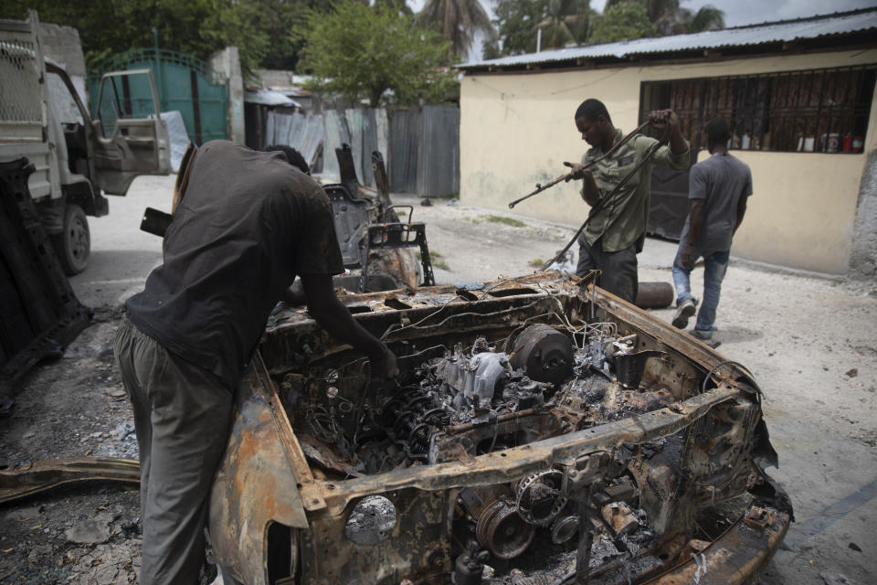 Men salvage parts from a charred car that was set on fire during clashes between armed gangs in the Butte Boyer neighborhood of Port-au-Prince, Haiti, Friday, May 13, 2022. Dozens of people, including women and children, have been killed in recent weeks amid new clashes between gangs fighting over territory as their power grows following the July 7 assassination of President Jovenel Moïse. (AP Photo/Odelyn Joseph)