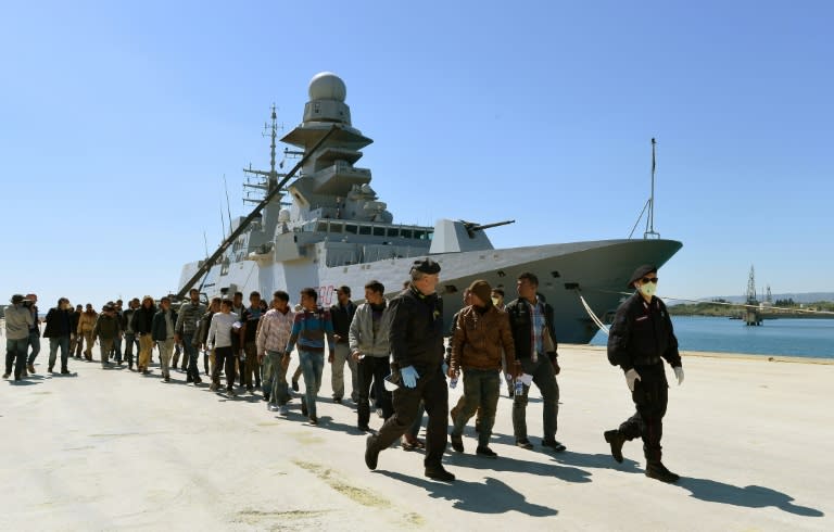 Rescued migrants walk along the quay after disembarking from the Italian Navy vessel Bettica as they arrive in the Sicilian harbour of Augusta on April 22, 2015