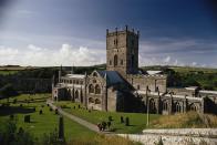 A family walking by St Davids Cathedral, Pembrokeshire, Wales.