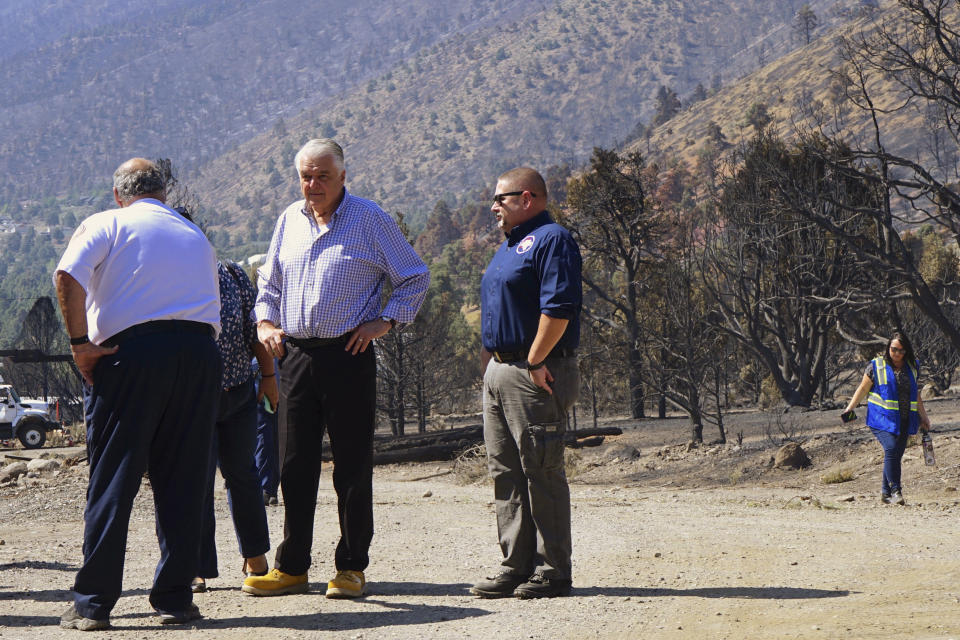 Nevada Gov. Steve Sisolak, second from left, tours areas of the forest damaged by wildfires near where the Tamarack Fire ignited earlier in July in Gardnerville, Nev., Wednesday, July 28, 2021. The governors of California and Nevada are calling for increased federal assistance as they tour an area blackened by one of several massive wildfires that have destroyed dozens of homes. Wednesday's tour of the Tamarack Fire along the state line comes as numerous wildfires char land and homes in a dozen states. (AP Photo/Sam Metz)