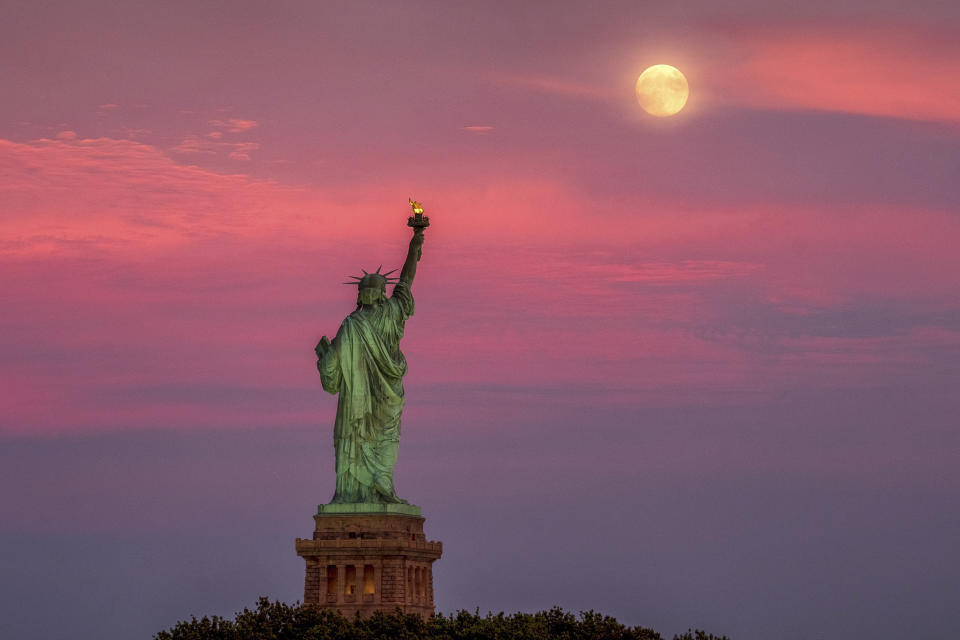 The full moon rises behind the Statue of Liberty at sunset in New York City, Monday, July 15, 2019, on the night before the 50th anniversary of the Apollo 11 moon launch. (AP Photo/J. David Ake)