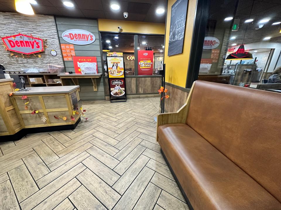 Interior of Denny's with brown seating area, check-in counter, and gray and red sign