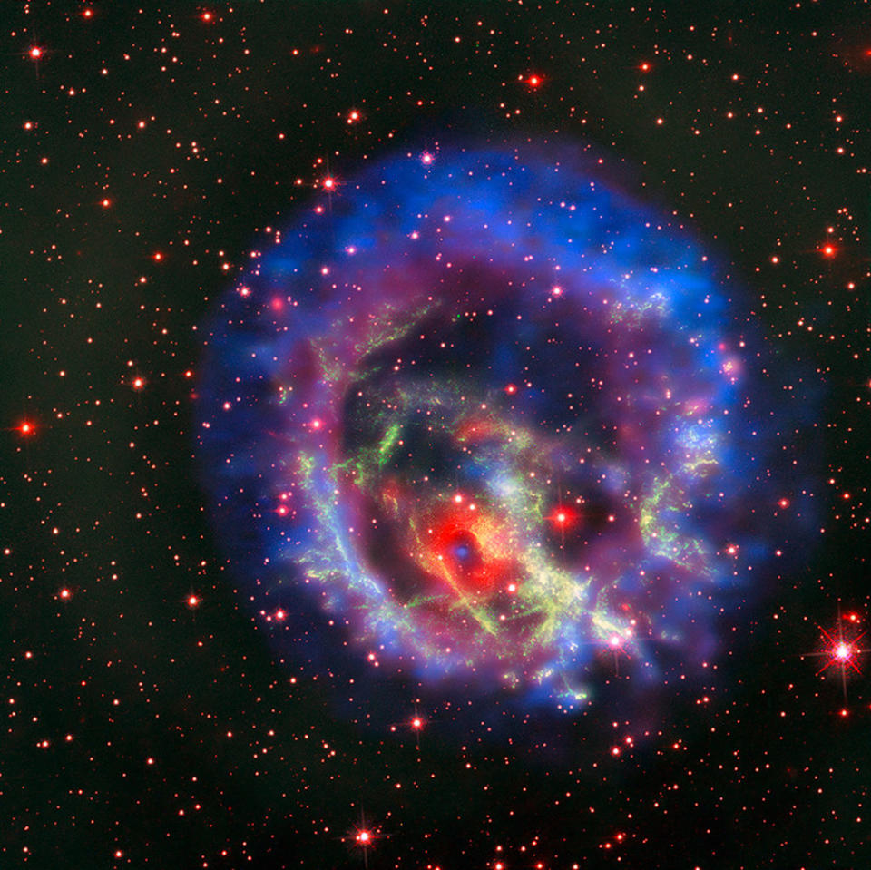 The new composite image of neutron star E0102, released on May 23, combines data from NASA's Chandra X-Ray Observatory (seen in blue and purple), the Multi Unit Spectroscopic Explorer instrument on the European Southern Observatory's Very Large Telescope in Chile (in bright red) and the Hubble Space Telescope (in dark red and green). <cite>X-ray (NASA/CXC/ESO/F.Vogt et al); Optical (ESO/VLT/MUSE & NASA/STScI)</cite>