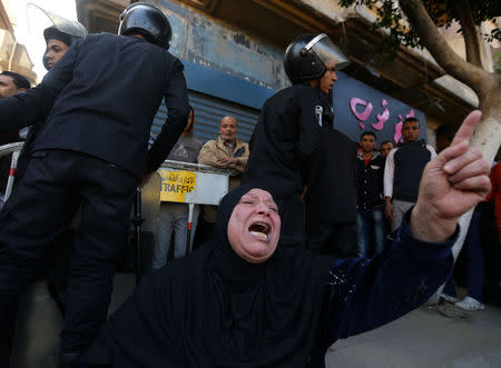 A Muslim woman cries while sitting in front of police officers in front of St. Mark's Coptic Orthodox Cathedral after an explosion inside the cathedral in Cairo, Egypt December 11, 2016. REUTERS/Mohamed Abd El Ghany