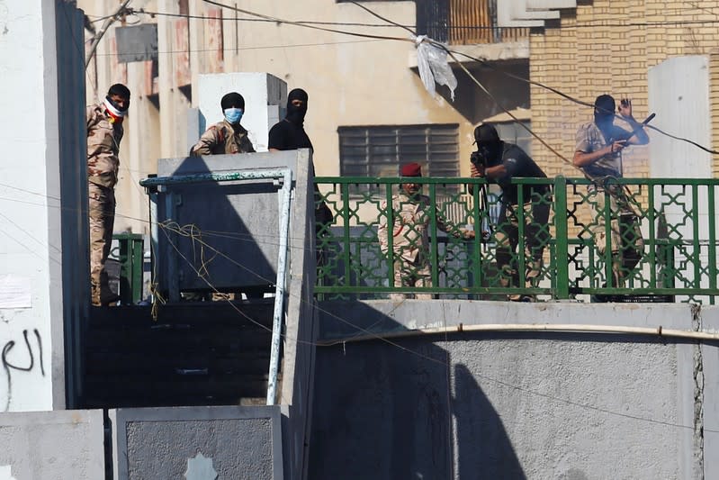 A member of Iraqi security forces points his gun towards the demonstrators during the ongoing anti-government protests in Baghdad