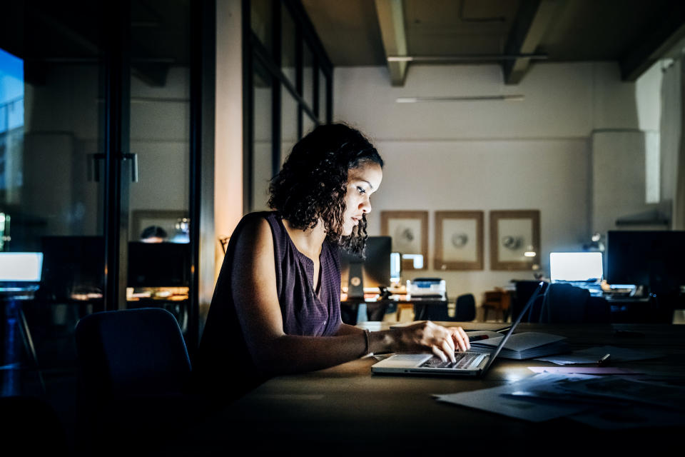 Casual young businesswoman working late on a laptop computer in a modern office space