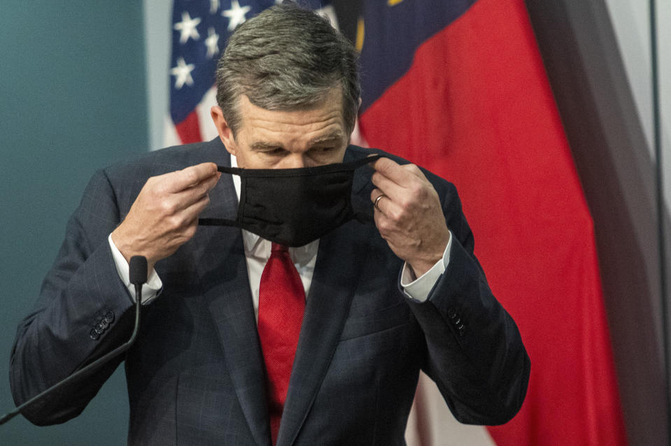 Gov. Roy Cooper removes his mask before answering a reporter's question during a briefing on North Carolina's coronavirus pandemic response at the North Carolina Emergency Operations Center, Wednesday, Sept. 30, 2020, in Raleigh, N.C. (Travis Long/The News & Observer via AP)