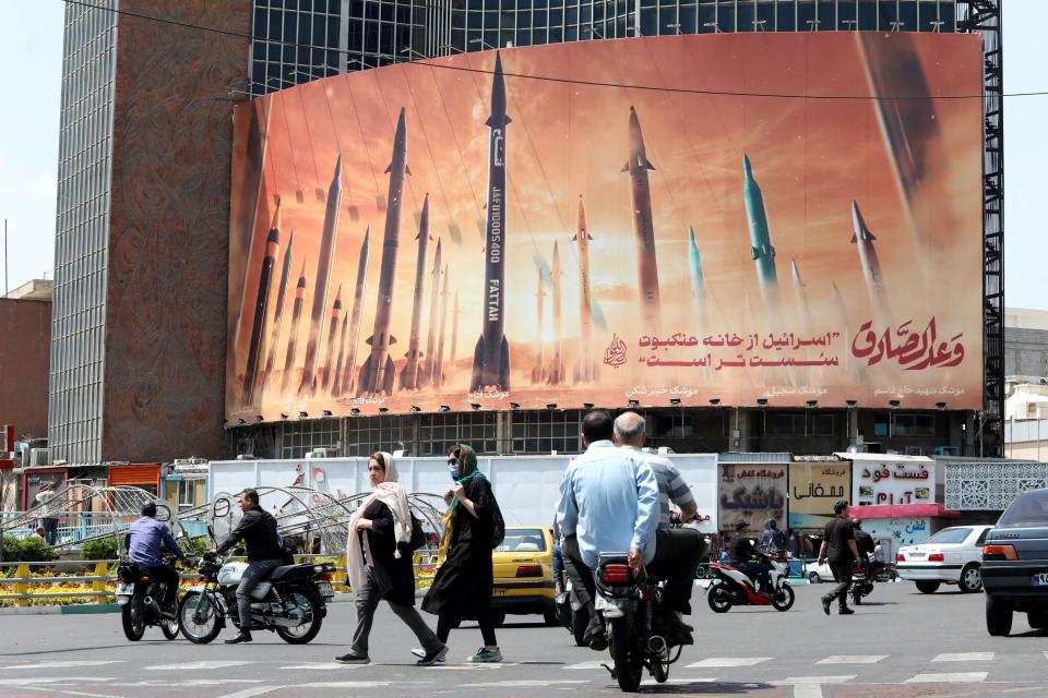 Motorists drive their vehicles past a billboard depicting Iranian missiles in Tehran on April 20, 2024, a day after Iran's state media reported explosions in the central province of Isfahan.