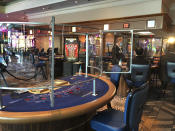 In this May 22, 2020 photo, a masked blackjack dealer at Foxwoods Resort Casino in Mashantucket, Conn., demonstrates how newly installed clear, plastic shields that surround table games, will work when the tribal-owned Foxwoods and neighboring Mohegan Sun expect to partially reopen on June 1. The Mashantucket Pequot and Mohegan Tribes are pushing ahead with plans to open their resorts on tribal lands, despite opposition from Connecticut Gov. Ned Lamont. (AP Photo/Susan Haigh)