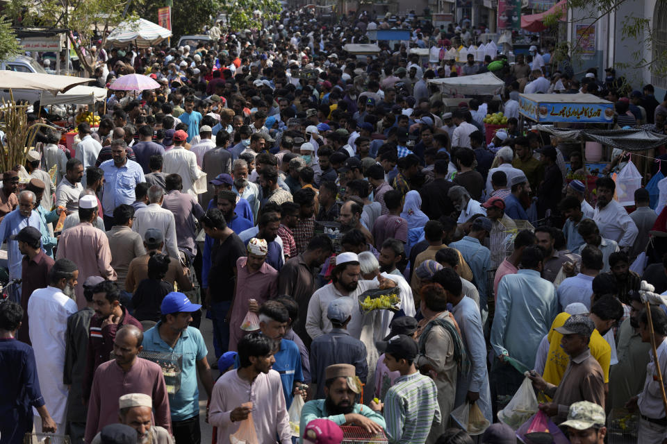 Pakistanis shops in a weekly pet market in Lahore, Pakistan, Monday, Nov. 13, 2022. The 8 billionth baby on Earth is about to be born on a planet that is getting hotter. But experts in climate science and population both say the two issues aren't quite as connected as they seem. (AP Photo/Fareed Khan)