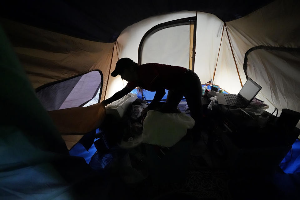 Cristin Trahan closes the windows of her tent to change from her work clothes where the family's home was destroyed in Lake Charles, La., Friday, Dec. 4, 2020. They were hit by Hurricanes Laura and Delta. She, her husband and a son are living in a tents, while her other son, his fiancée and their one-year old son are living in a loaned camper there. A relative's home on the same property is now gutted and they are living in a camper as well. (AP Photo/Gerald Herbert)