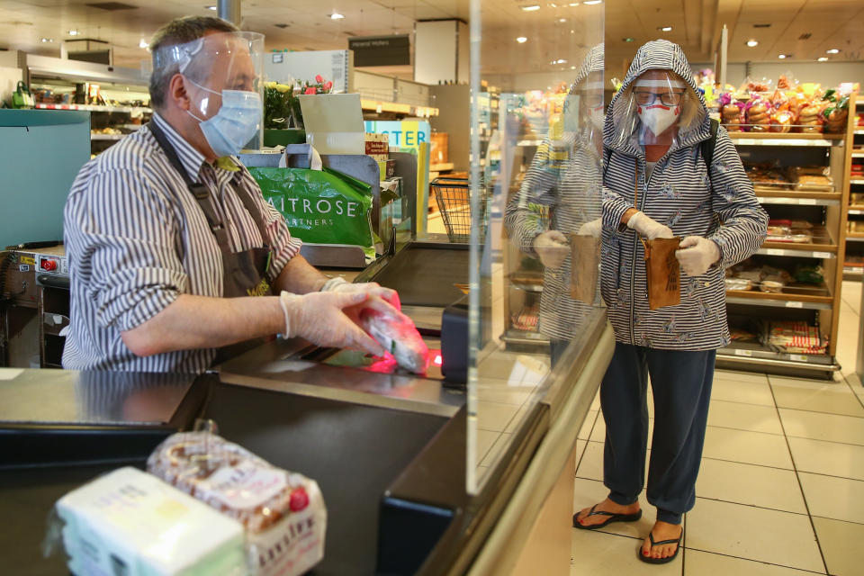 LONDON, ENGLAND - APRIL 13: A Waitrose employee scans groceries while wearing personal protective equipment on April 13, 2020 in South West London, United Kingdom. The Coronavirus (COVID-19) pandemic has spread to many countries across the world, claiming over 110,000 lives and infecting over 1. 8 million people.  (Photo by Hollie Adams/Getty Images)