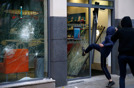 A youth breaks a window of an insurance agency during a demonstration of the "yellow vests" movement in Nantes, France, January 26, 2019. REUTERS/Stephane Mahe