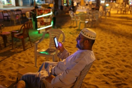 Palestinian man uses his mobile phone as he sits in an outdoor rest area in Khan Younis in the southern Gaza Strip