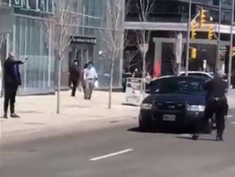 A lone police officer (R) confronts the man suspected of driving a van into pedestrians in Toronto (L) as he points an object that looks like a gun (rayy0889/Twitter/Screengrab)