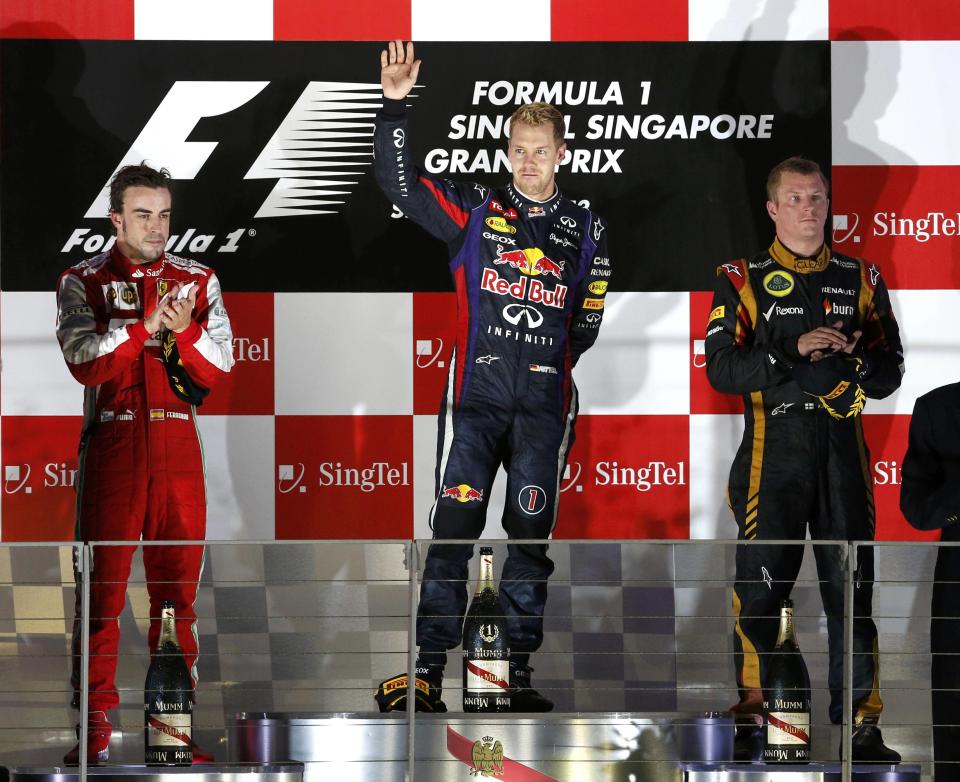 Red Bull Formula One driver Sebastian Vettel of Germany (C), Ferrari Formula One driver Fernando Alonso of Spain (L) and Lotus F1 Formula One driver Kimi Raikkonen of Finland (R) stand on the podium after the Singapore F1 Grand Prix at the Marina Bay street circuit in Singapore September 22, 2013. Vettel cruised to a third straight Singapore Grand Prix victory on Sunday and moved closer to a fourth consecutive Formula One world title with a dominant drive under the floodlights at the Marina Bay Street Circuit. REUTERS/Edgar Su (SINGAPORE - Tags: SPORT MOTORSPORT F1)