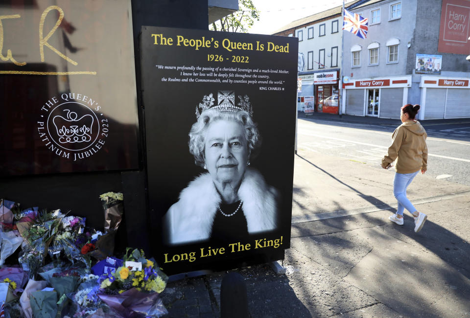 FILE - A woman walks past a picture of Queen Elizabeth II on the Loyalist Shankill Road in west Belfast, Sept. 10, 2022. Britain's longest-reigning monarch and a rock of stability across much of a turbulent century, died Thursday Sept. 8, 2022. (AP Photo/Peter Morrison, File)