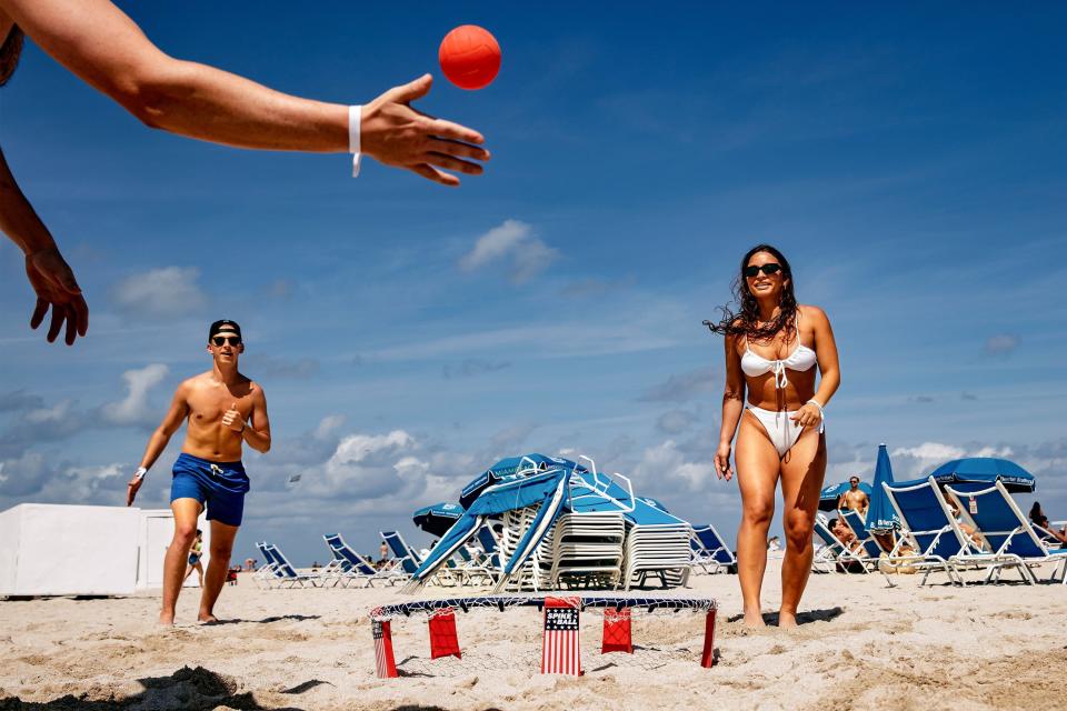 From left, Chandler Robinson, Sam Fisher and Alexis Illes play slam ball on South Beach in Miami Beach, Fla. on Friday, March 31, 2023, while vacationing from Orlando, Fla. After a series of violent incidents, the city is moving to pre-empt late-night partying, but businesses worry about crimping their most profitable tourism season. (Scott McIntyre/The New York Times)