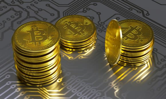 Physical gold bitcoins atop a digital matrix.