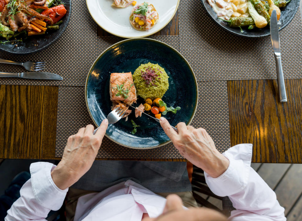 a hand holding silverware cutting food