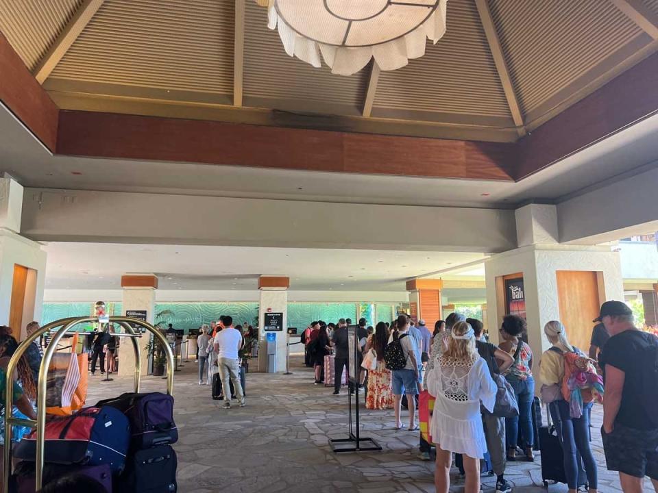 A line of people waiting in a hotel lobby to check-in.