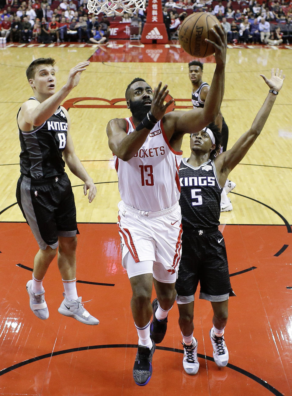 Houston Rockets guard James Harden (13) drives to the basket as Sacramento Kings guard Bogdan Bogdanovic (8) and guard De'Aaron Fox defend during the first half of an NBA basketball game, Saturday, March 30, 2019, in Houston. (AP Photo/Eric Christian Smith)