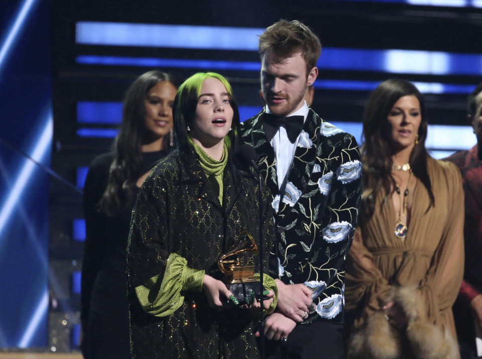 Billie Eilish, left, and Finneas O'Connell accept the award for song of the year for "Bad Guy" at the 62nd annual Grammy Awards on Sunday, Jan. 26, 2020, in Los Angeles. At right looking on is presenter Karen Fairchild. (Photo by Matt Sayles/Invision/AP)