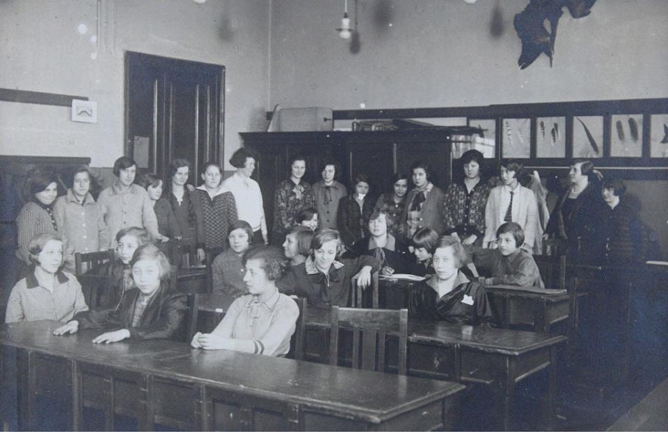 A group portrait of teachers and pupils around the age of 14 in a classroom, circa 1925