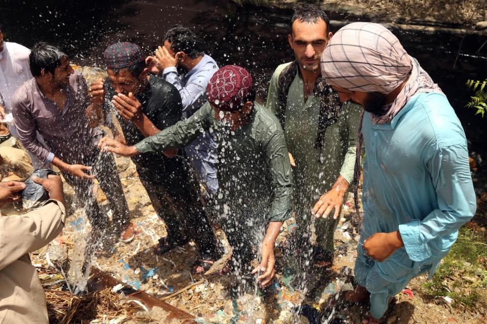 People cool off around punctured water supply lines as heatwave continue in Karachi, Pakistan (EPA)