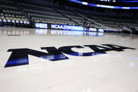 FILE - In this March 18, 2015, file photo, the NCAA logo is displayed on the court as work continues at The Consol Energy Center in Pittsburgh. Coaches did the best they could to prepare for the big moment, yet still find themselves in a scramble once it actually happened. The NCAA announced last month that the season would begin on Nov. 25 and teams are still trying to fill all the holes in their schedules. (AP Photo/Keith Srakocic, File)