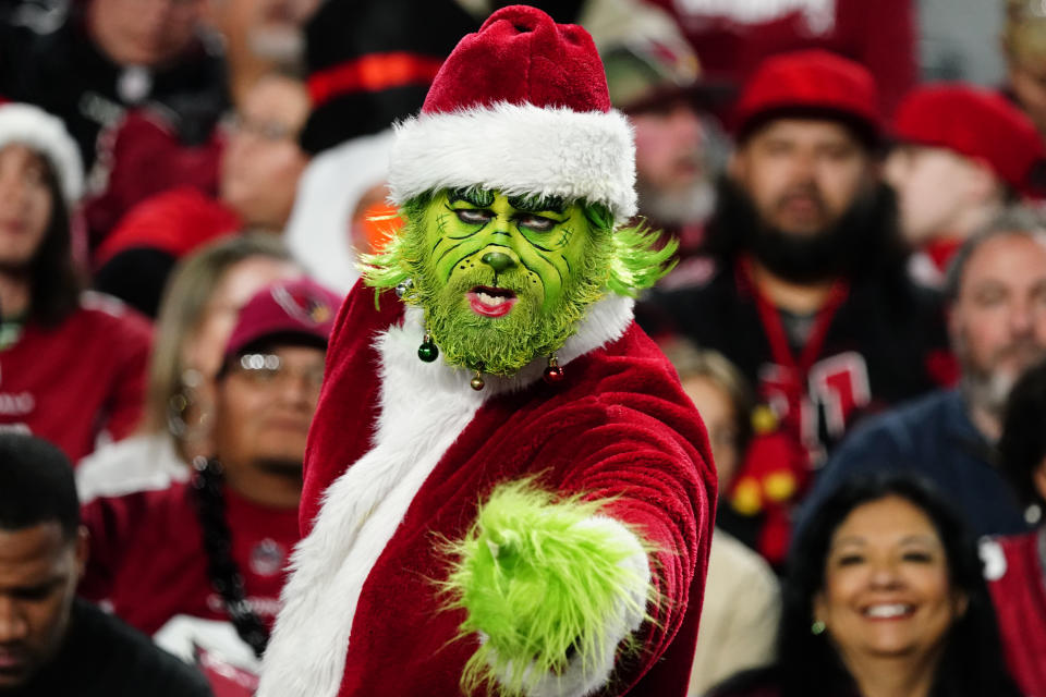 A fan dressed as the Grinch watches play during the first half of an NFL football game between the Arizona Cardinals and the Tampa Bay Buccaneers, Sunday, Dec. 25, 2022, in Glendale, Ariz. (AP Photo/Darryl Webb)