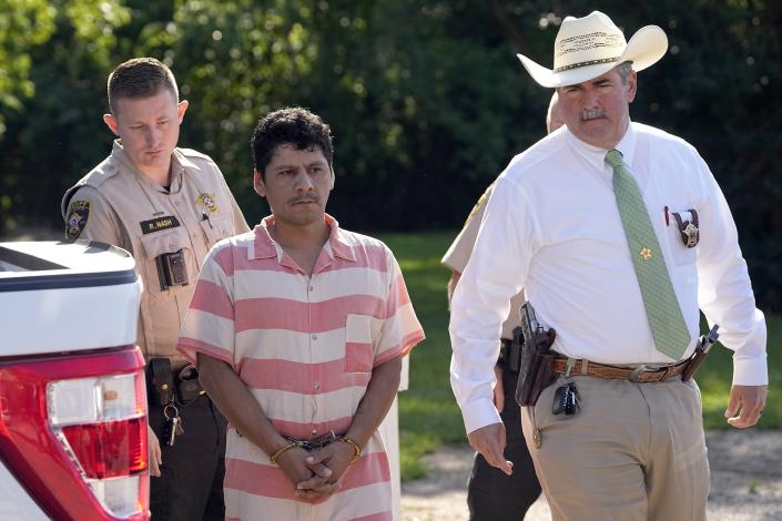 Francisco Oropeza, center, is escorted to the San Jacinto County courthouse by San Jacinto County Sheriff Greg Capers, right, for a hearing Thursday, May 18, 2023, in Coldspring, Texas. Oropeza is suspected of killing five people, including a 9-year-old boy, after neighbors asked him to stop firing off rounds in his yard. (AP Photo/David J. Phillip)