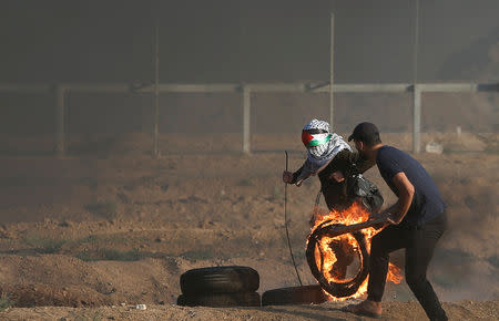 Palestinians push a burning tyre during a protest calling for lifting the Israeli blockade on Gaza and demanding the right to return to their homeland, at the Israel-Gaza border fence, east of Gaza City September 14, 2018. REUTERS/Mohammed Salem