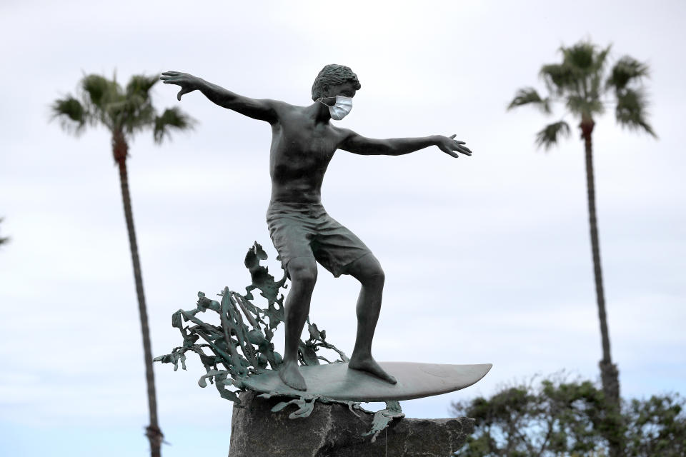 The "Magic Carpet Ride" statue in Cardiff-by-the-Sea, California wears a face mask to ward off the coronavirus. (Photo: Sean M. Haffey/Getty Images)