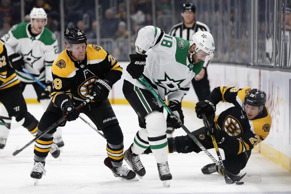 Dallas Stars' Jason Dickinson (18) battles Boston Bruins' Ondrej Kase (28) and Par Lindholm (26) for the puck during the third period of an NHL hockey game in Boston, Thursday, Feb. 27, 2020. (AP Photo/Michael Dwyer)