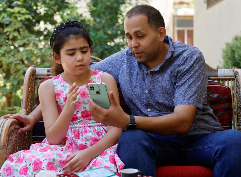 Palestinian Americans Hani Almadhoun and his daughter Zayna sit in their home in Beit Lahiya