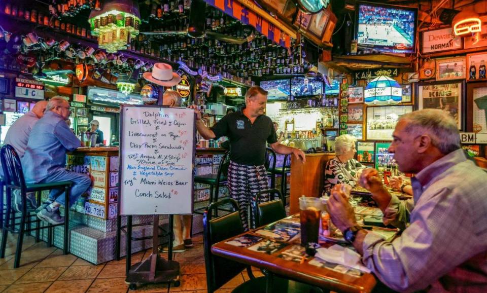 El propietario Wayne Russell desplaza un pizarrón con las especialidades del día por Duffy's Tavern en Miami.