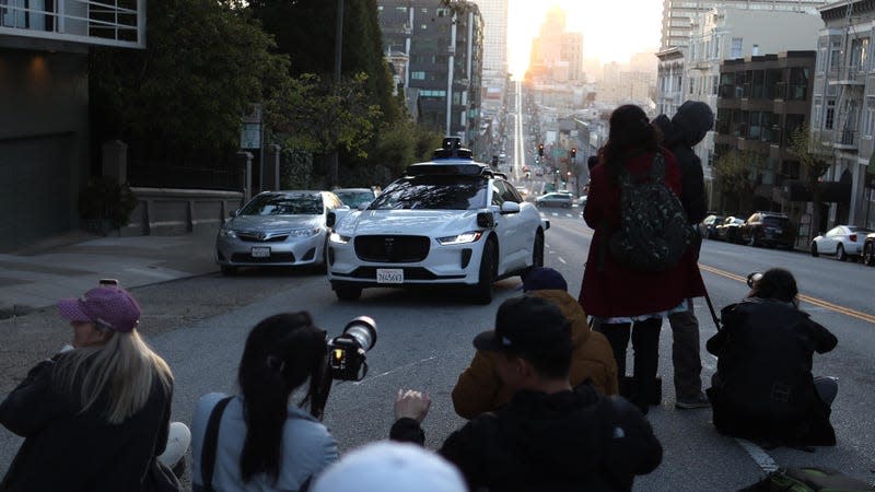 A Waymo self-driving car stops while driving as people stand in the middle of the street to photograph the sunrise on April 09, 2024 in San Francisco, California. - Photo: Justin Sullivan (Getty Images)