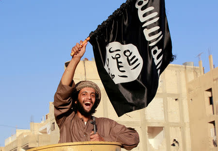 FILE PHOTO – A militant Islamist fighter waving a flag, cheers as he takes part in a military parade along the streets of Syria’s northern Raqqa province June 30, 2014. REUTERS/Stringer/File Photo